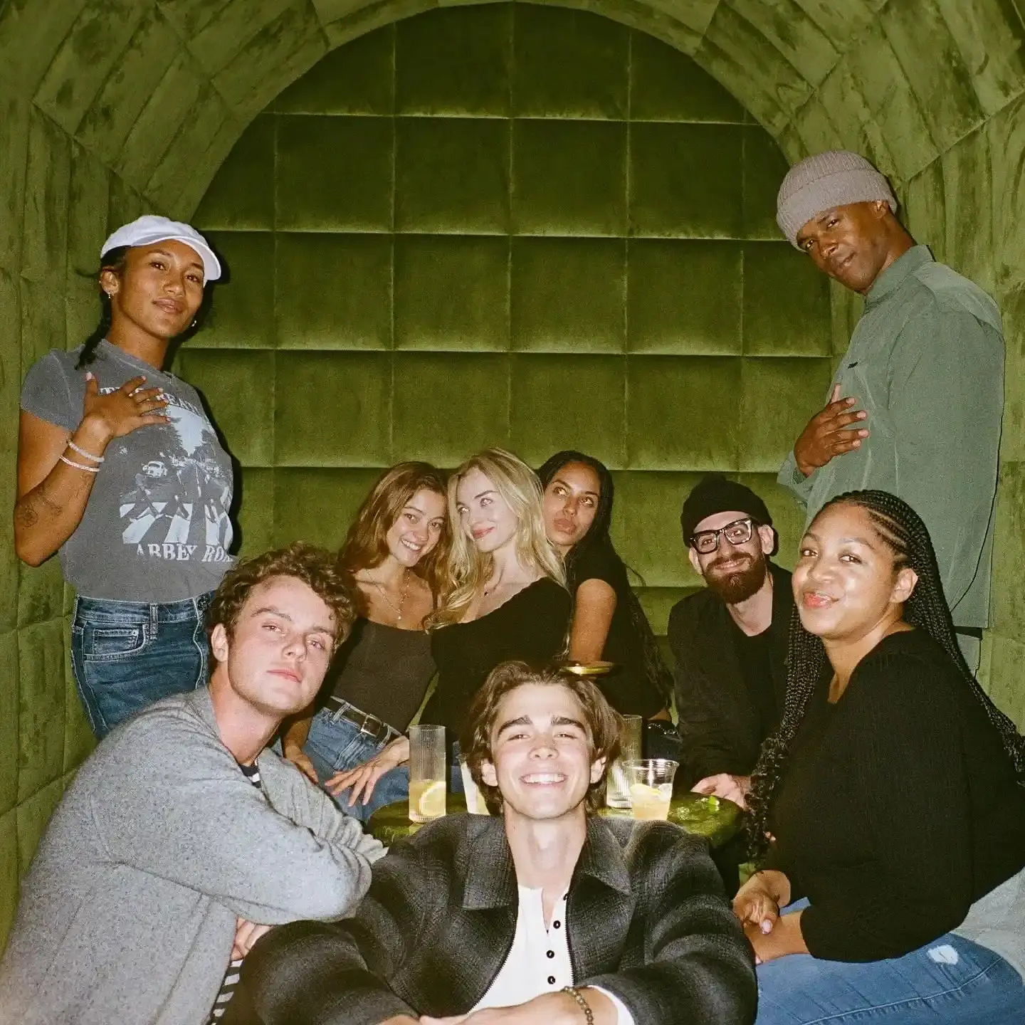 The cast of Scary Movie 6 poses together inside a green velvet-tufted booth.