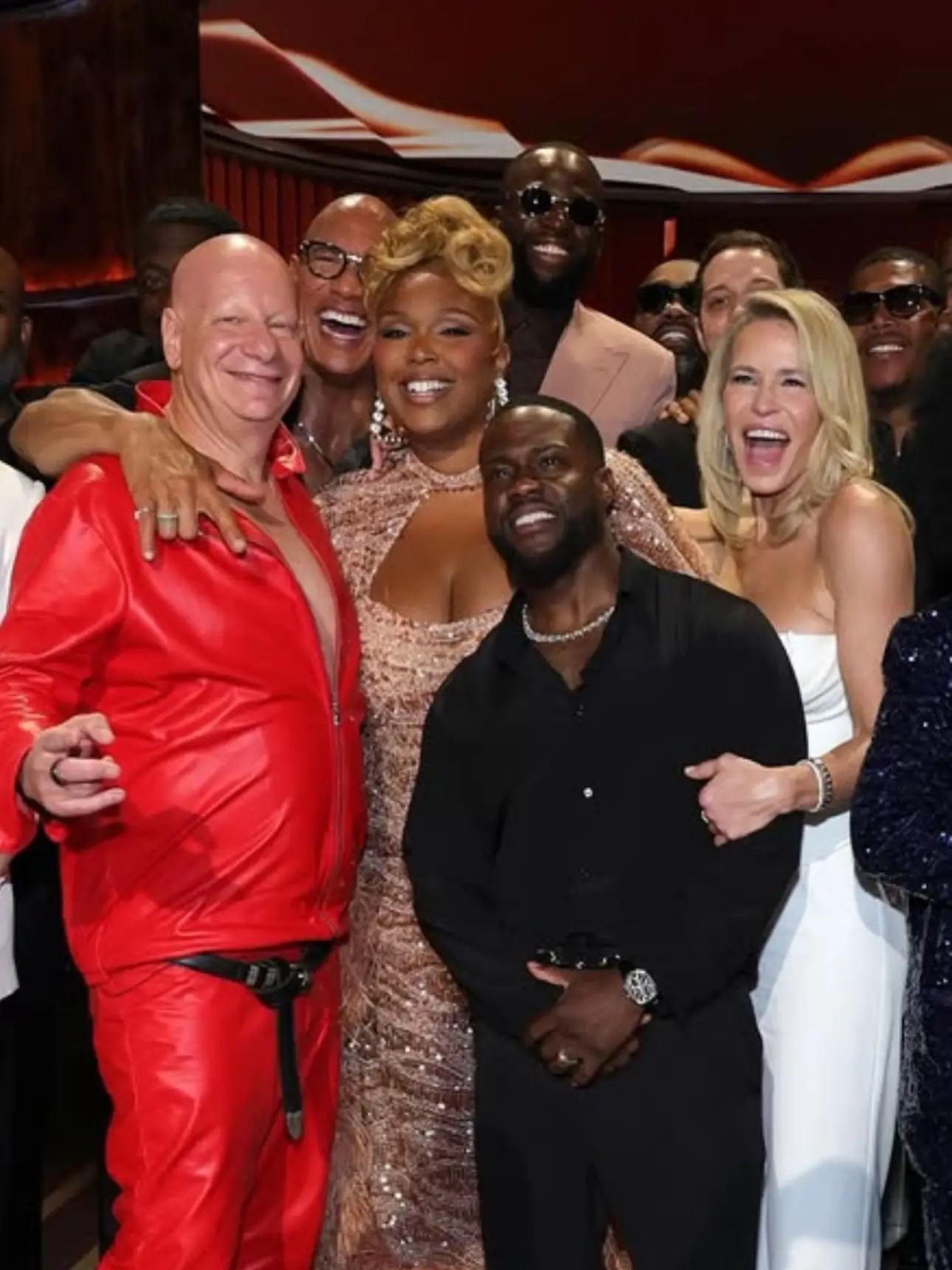 A cheerful group of celebrities, including Kevin Hart and Lizzo, smile and pose closely together at an awards event.