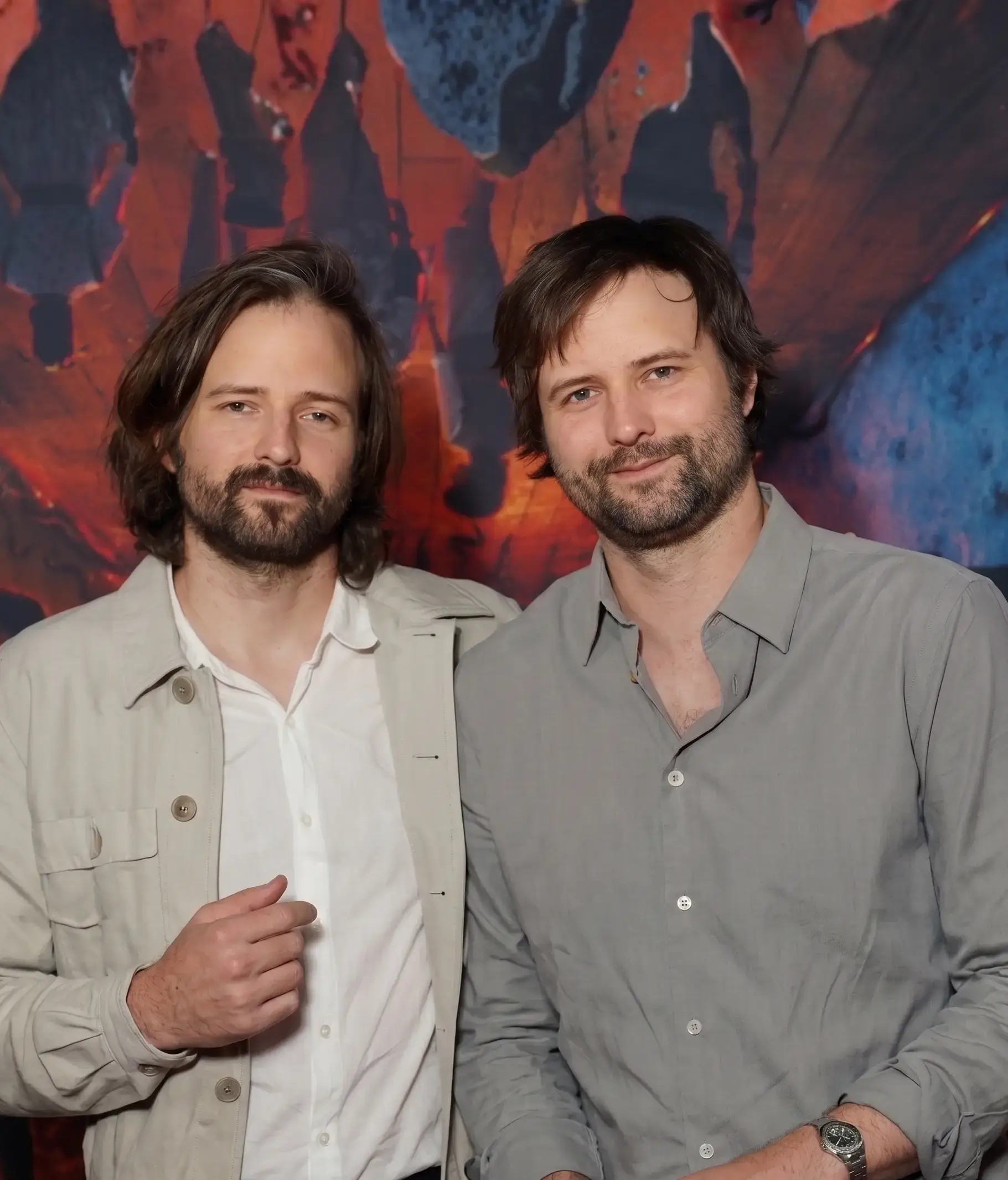 Twin filmmakers Matt and Ross Duffer, known as the Duffer brothers, pose together smiling in casual button-down shirts.
