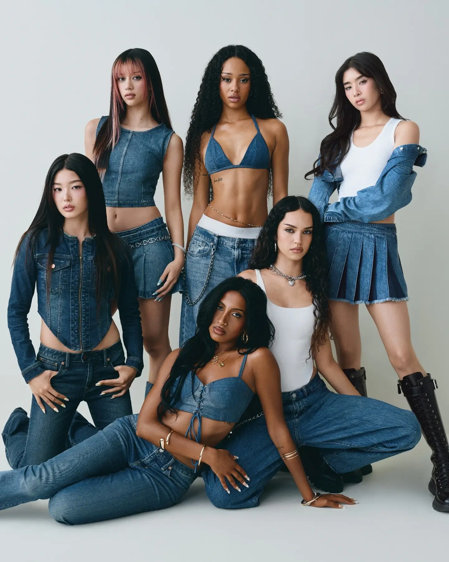 The six members of the global girl group KATSEYE pose together against a white background wearing coordinated blue denim outfits.