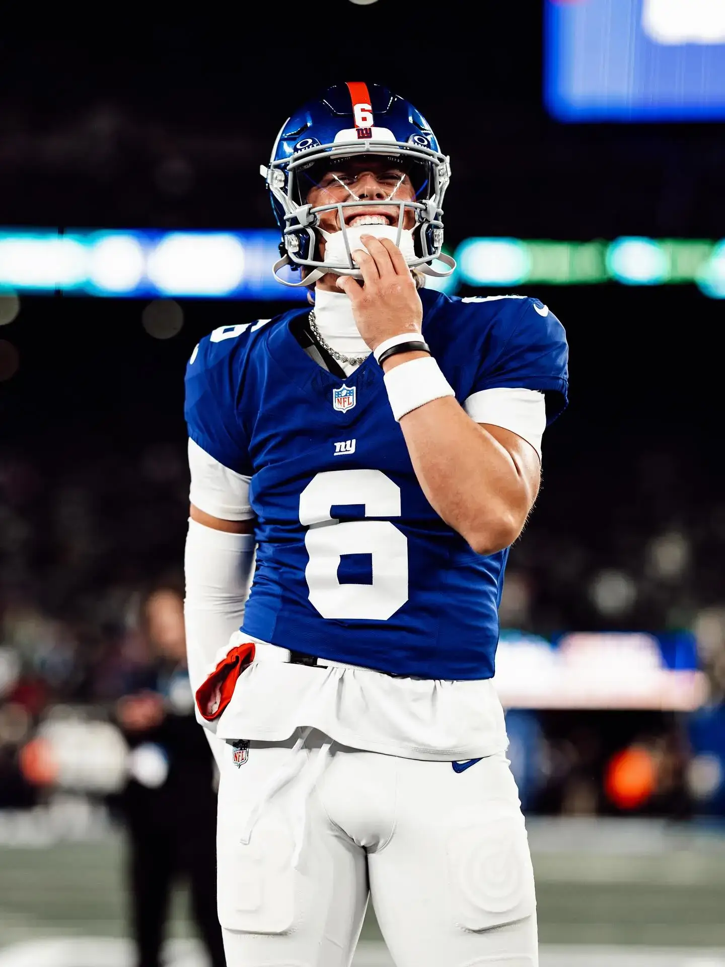 Football player Jaxson Dart smiles on the field while wearing a blue and white New York Giants jersey with the number six.