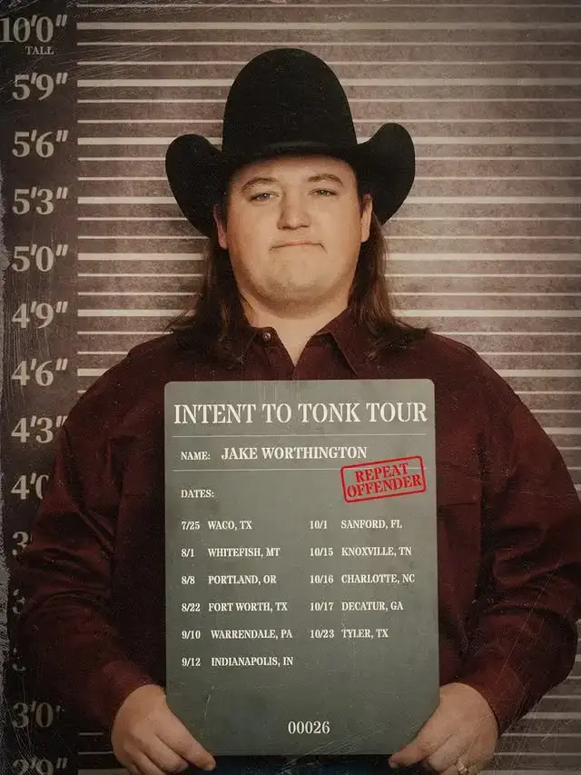Jake Worthington poses in a cowboy hat for a mock mugshot backdrop while holding a sign detailing his "Intent to Tonk Tour" dates.