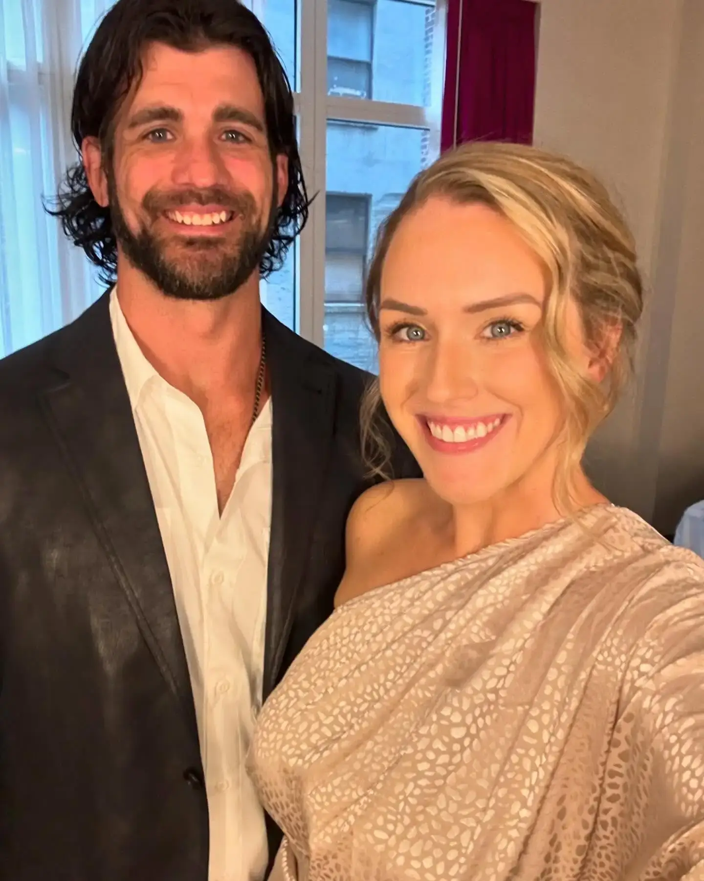 Jen Hamilton in a beige one-shoulder patterned dress stands smiling next to her ex-husband, Brian Hamilton, who is wearing a dark blazer and open white shirt.