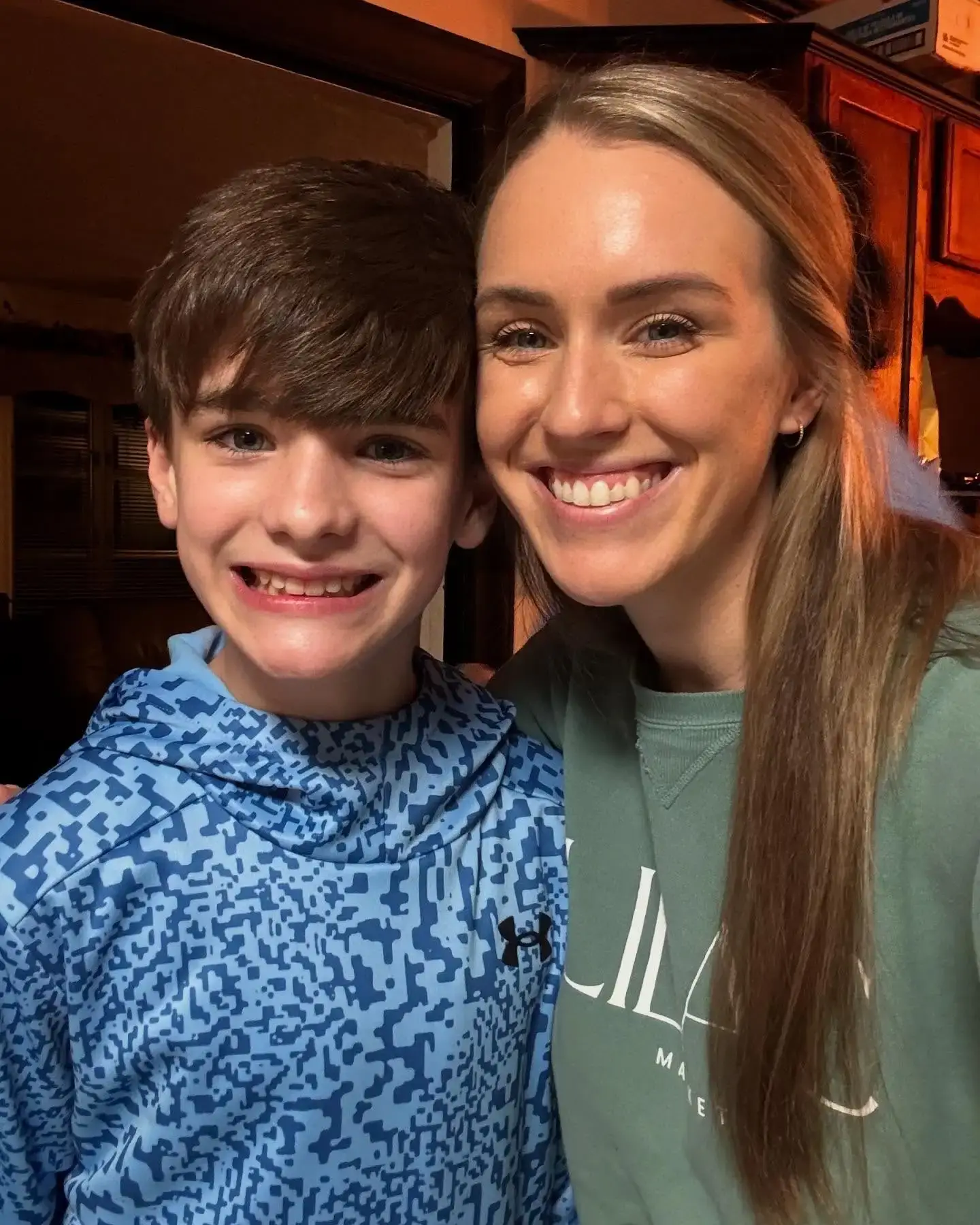 Jen Hamilton smiles brightly with her head leaned against her young son, Ellis Bean, who is wearing a blue patterned Under Armour hoodie.