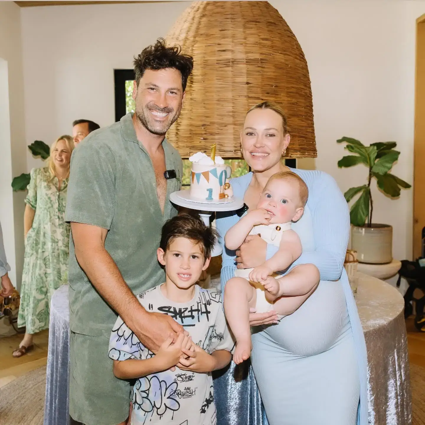 Professional dancers Peta Murgatroyd and Maks Chmerkovskiy smile with their two young sons next to a first birthday cake.