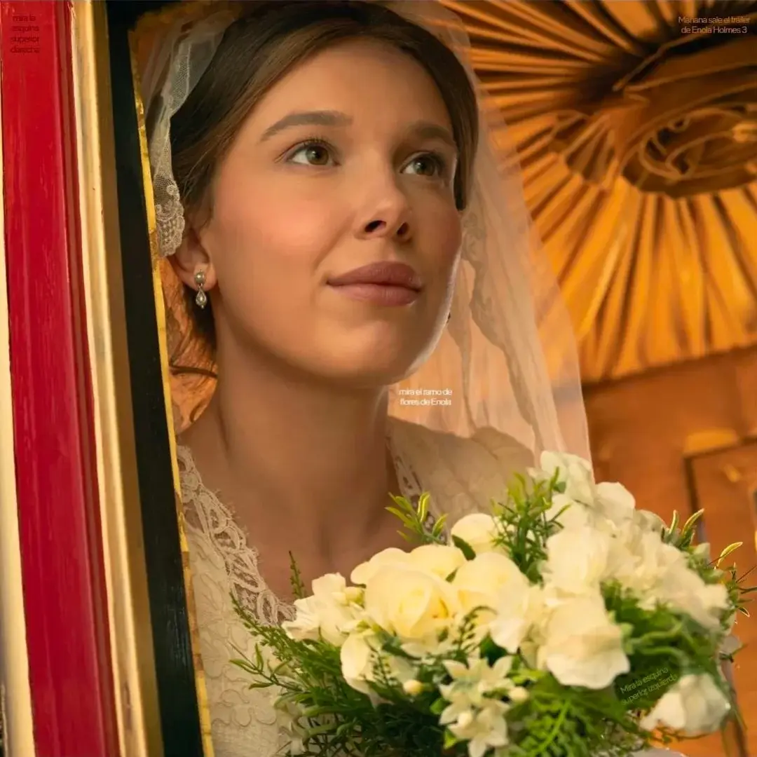 Millie Bobby Brown as Enola Holmes wears a white lace dress and bridal veil while holding a bouquet of white roses inside a carriage.