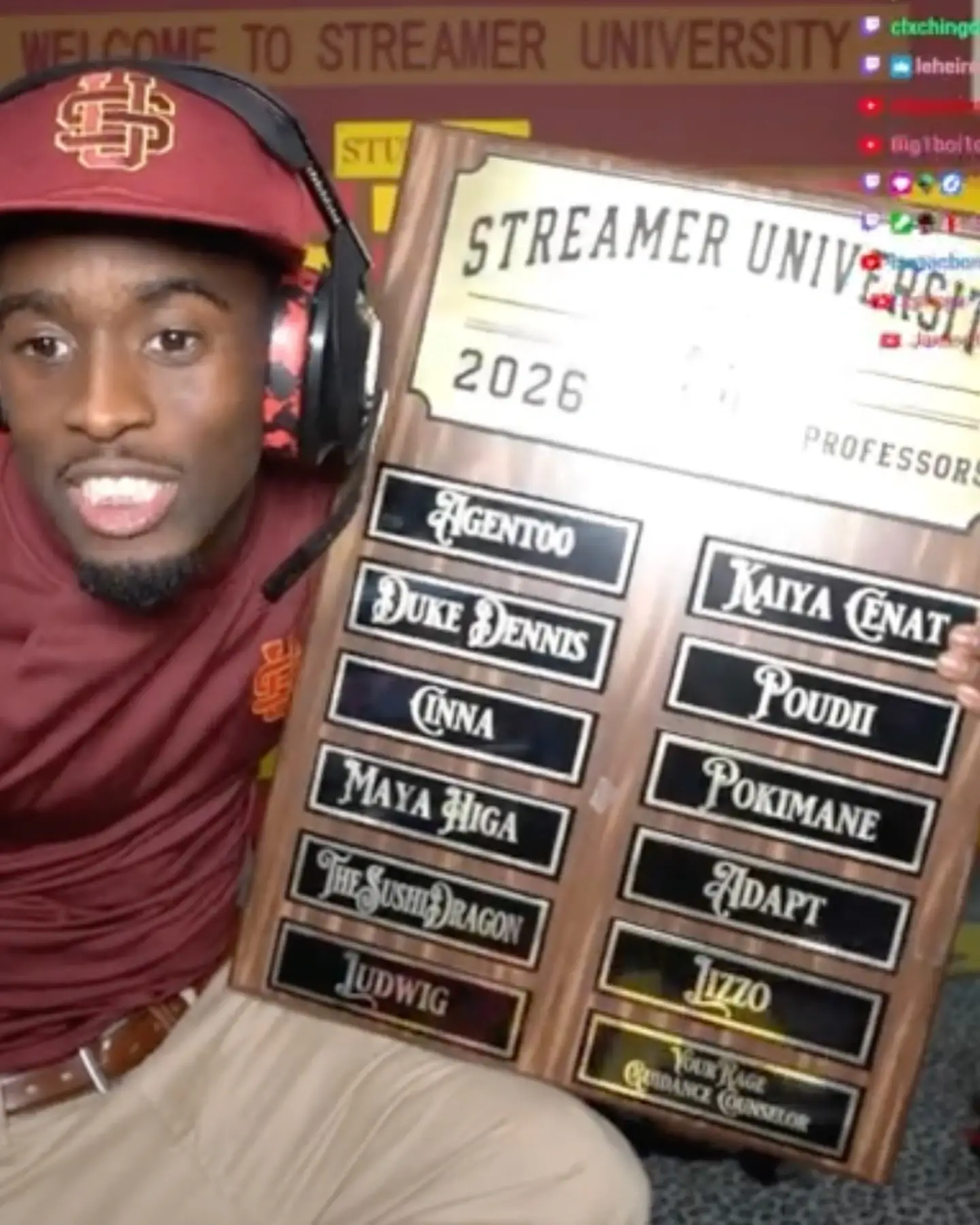 Kai Cenat smiles while holding a large wooden "Streamer University 2026 Professors" plaque listing popular content creators.