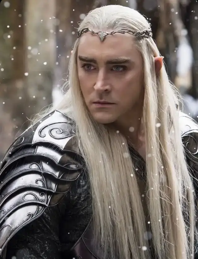 Actor Lee Pace as Thranduil from The Hobbit movies with long platinum blonde hair, a silver crown, and intricate armor amidst falling snow.
