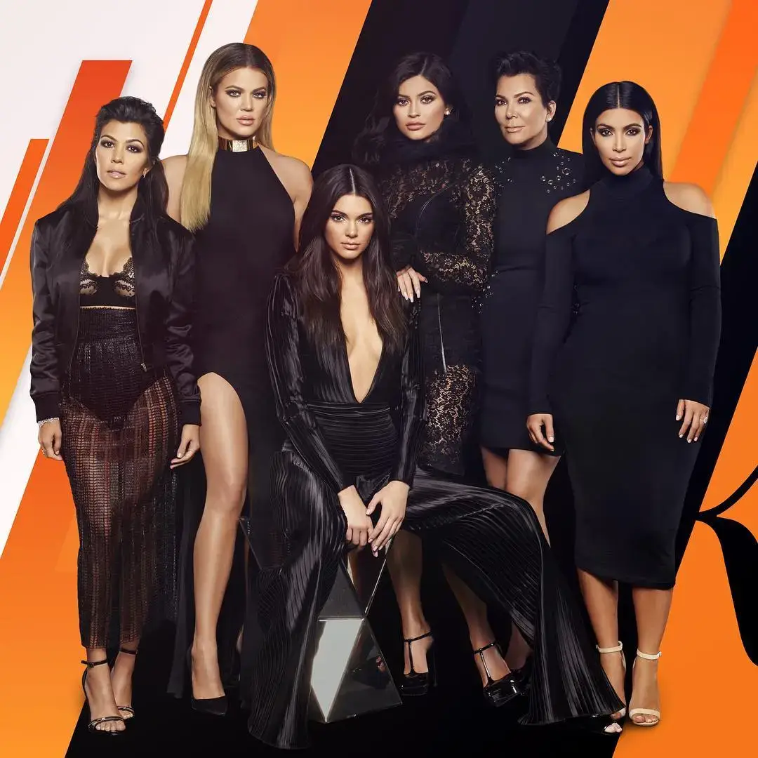 A group promotional portrait of Kourtney, Khloé, Kendall, Kylie, Kris, and Kim Kardashian wearing all-black outfits against an orange and black geometric background.