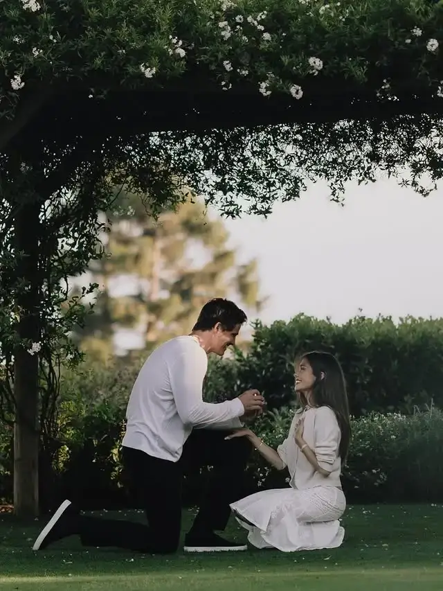 Justin Herbert proposes on one knee to Madison Beer in a lush garden setting.