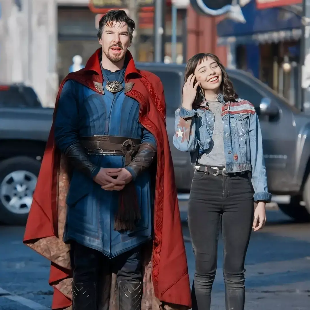 Benedict Cumberbatch as Doctor Strange and Xochitl Gomez as America Chavez stand together on a street in costume.