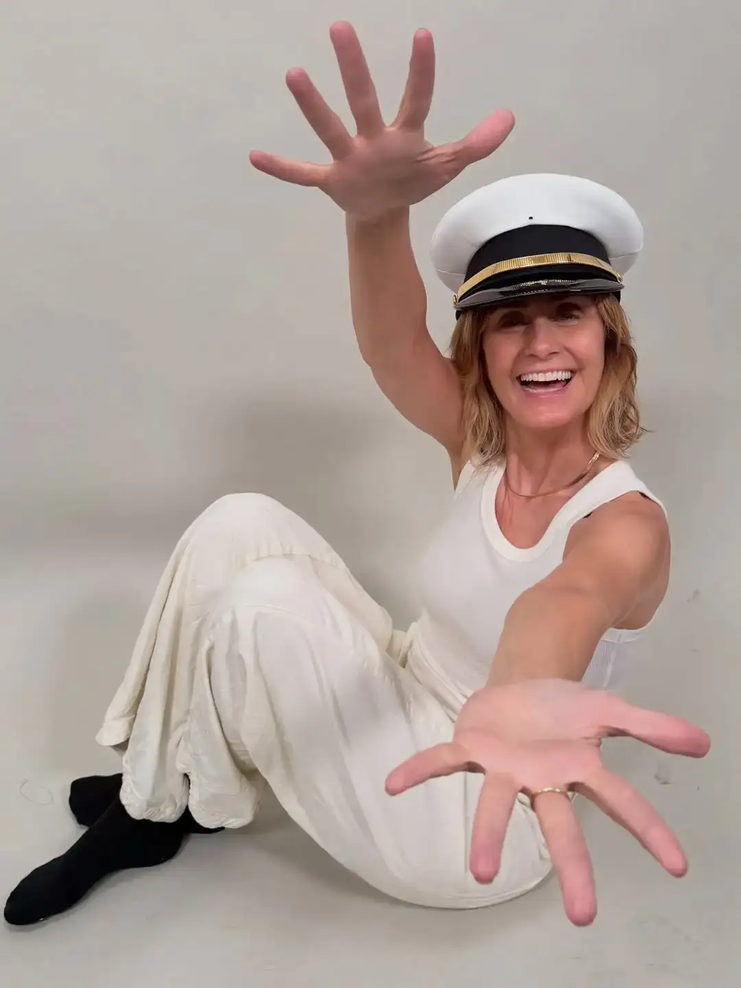 Diane Farr sitting in an all-white outfit and a captain