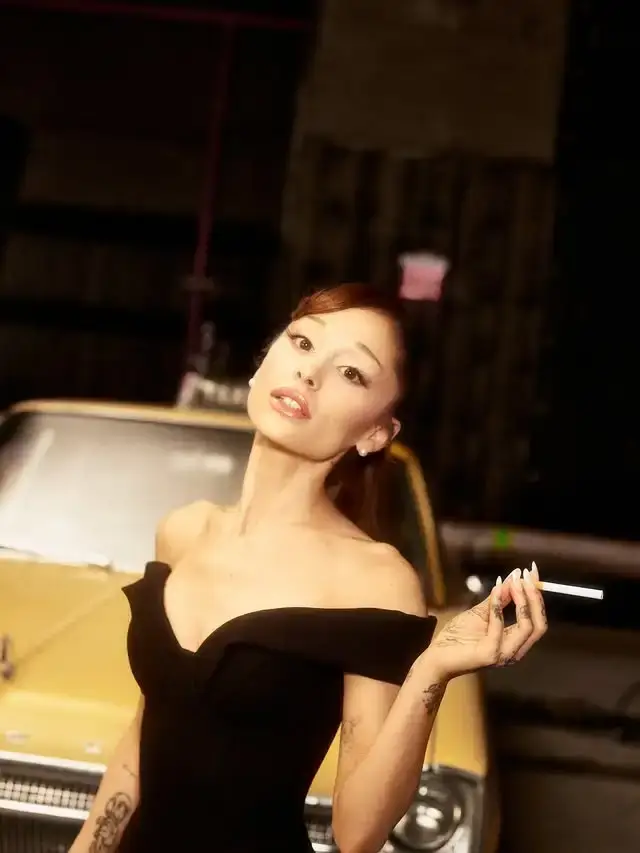 Ariana Grande posing in an off-the-shoulder black dress holding a cigarette in front of a classic yellow car.