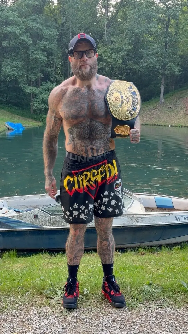 Dalton Ain’t Worried in tattoo standing shirtless near a lake holding a World Heavyweight Championship belt