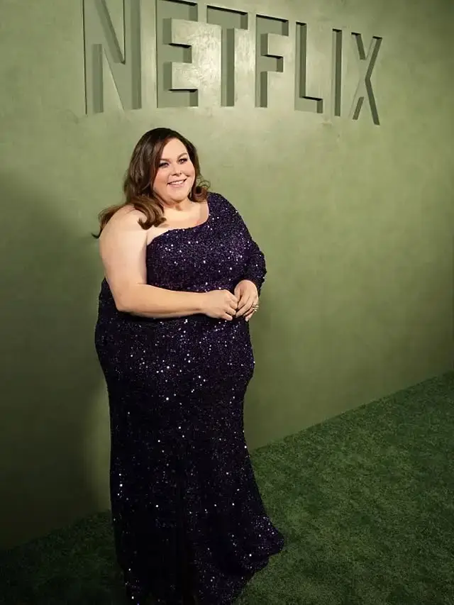 Chrissy Metz smiling in a sparkling dark purple one-shoulder sequin gown against a green Netflix backdrop.