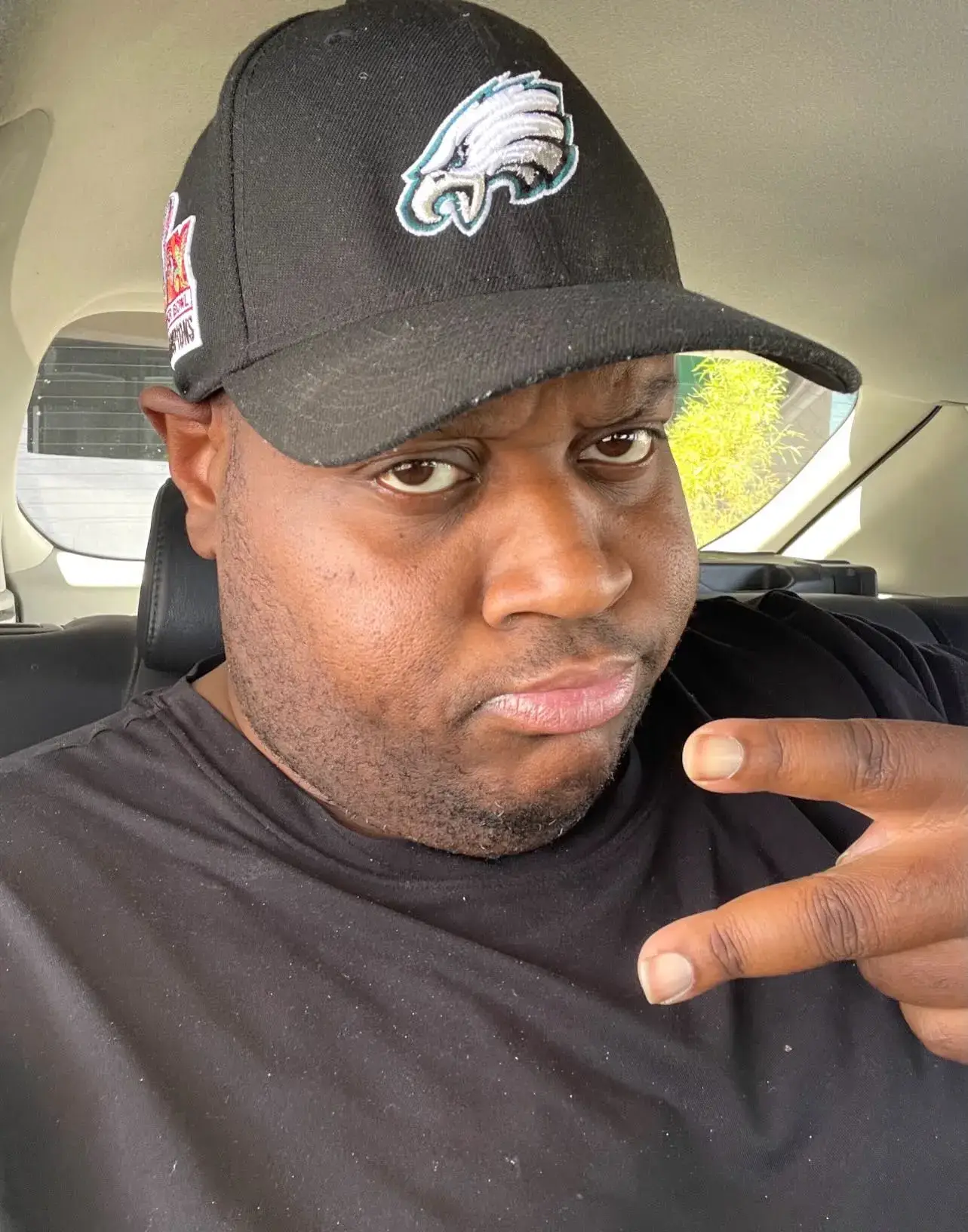 Bryant Moreland, known as EDP445, taking a car selfie while wearing a black Philadelphia Eagles baseball cap and black t-shirt.