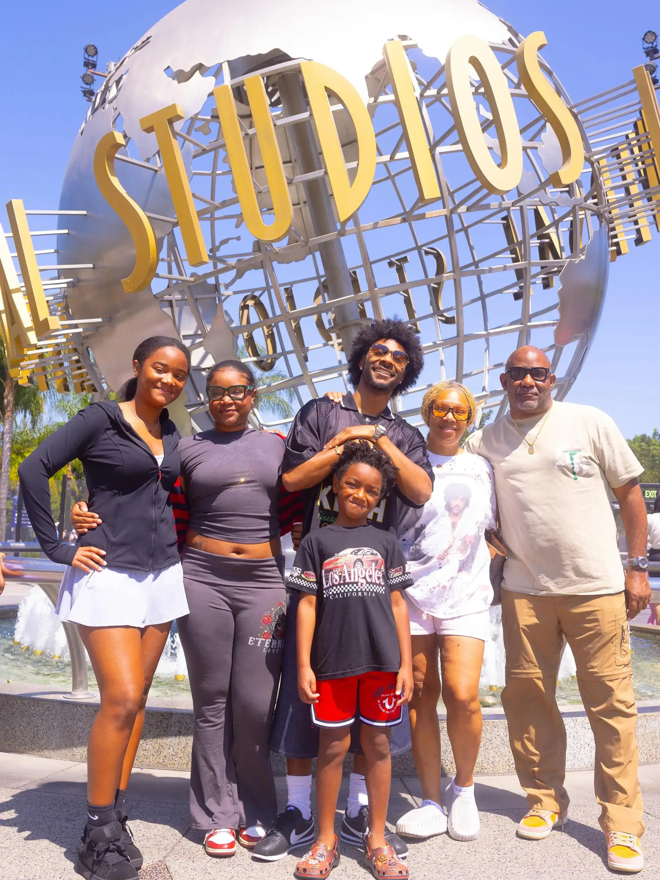 Jonathan Daviss smiles and poses outdoors with his family in front of the iconic Universal Studios globe.