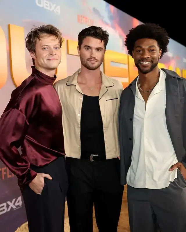 Rudy Pankow and Chase Stokes, alongside Jonathan Daviss, posing together on the red carpet at an Outer Banks event.