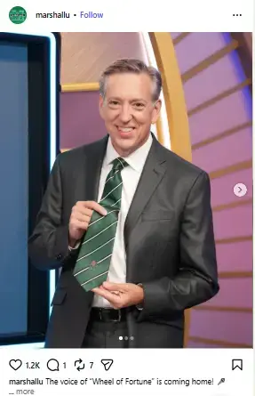 Jim Thornton smiling on the set of Wheel of Fortune while holding out his green striped necktie.