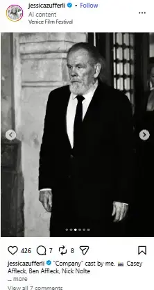 Black-and-white portrait of Nick Nolte sporting a full white beard and wearing a formal black suit with a tie.