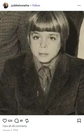 Vintage childhood photo of Judd Nelson as a young boy with straight bangs wearing a suit jacket and tie.