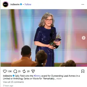 Sally Field smiling onstage in a sparkling blue dress while holding an Emmy Award statuette at the podium.
