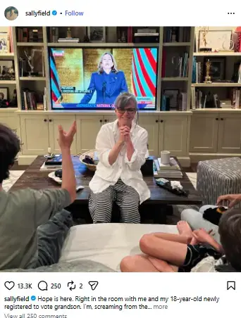 Sally Field smiling with hands clasped as she sits in her living room watching a speech on television surrounded by family.