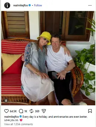 Tracy Pollan in a yellow bucket hat and Michael J. Fox sitting closely together on a wicker patio bench.