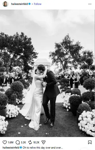 Black-and-white photo of Hailee Steinfeld in a strapless bridal gown kissing Josh Allen down the flower-lined wedding aisle.
