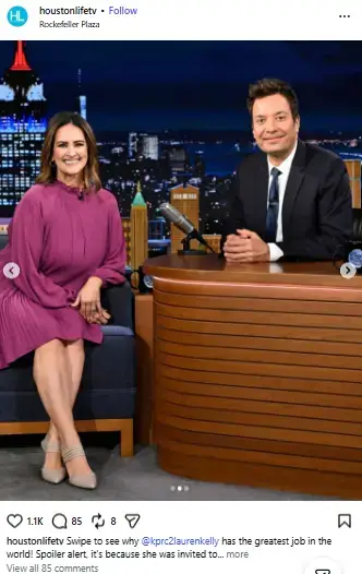 Lauren Kelly in a magenta dress smiling on set next to Jimmy Fallon seated at his talk show desk.