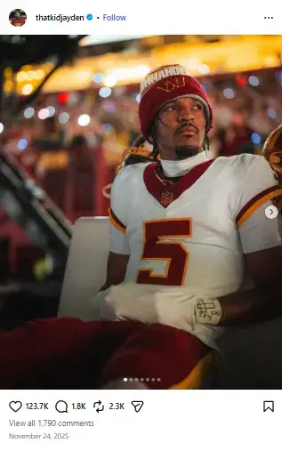 Washington Commanders quarterback Jayden Daniels sitting focused on the sideline bench wearing a team knit beanie and uniform.
