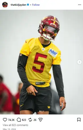 Jayden Daniels smiling on the practice field wearing a yellow Washington Commanders practice jersey and helmet