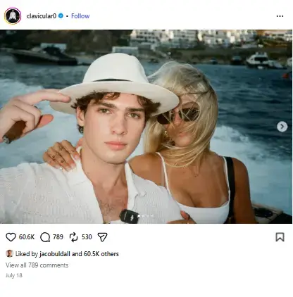 Braden Peters wearing a white fedora while holding a cigar next to Lily Snyder in sunglasses on a boat ride.