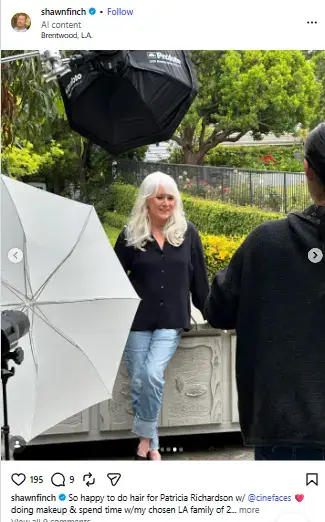 Patricia Richardson posing outdoors by a garden ledge in a black shirt and jeans surrounded by photography lighting gear.