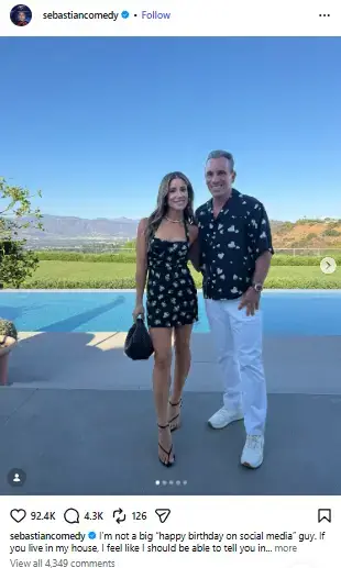 Sebastian Maniscalco standing beside his wife Lana Gomez in front of a scenic infinity pool and mountain view.