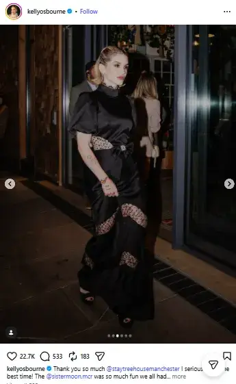Kelly Osbourne walking outside at night in a high-neck black gown featuring lace inserts, short puff sleeves, and a bow waist detail.
