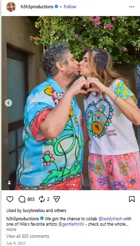 Ethan Klein and Hila Klein sharing a kiss while forming a heart with their hands wearing colorful printed Teddy Fresh outfits