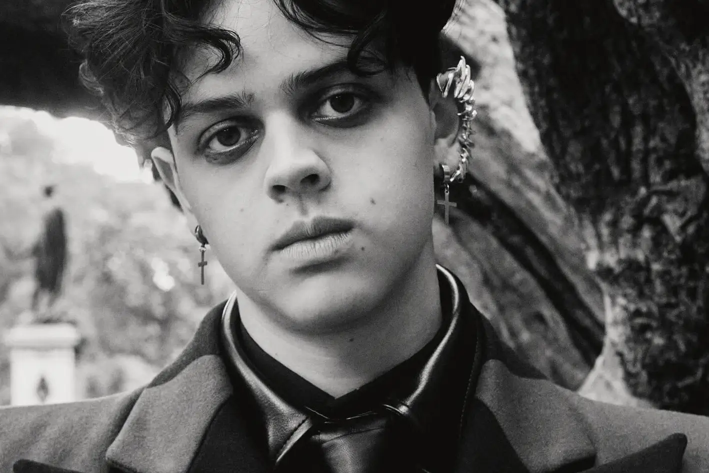 A close-up portrait of Isaac Ordonez with a serious expression and multiple earrings.