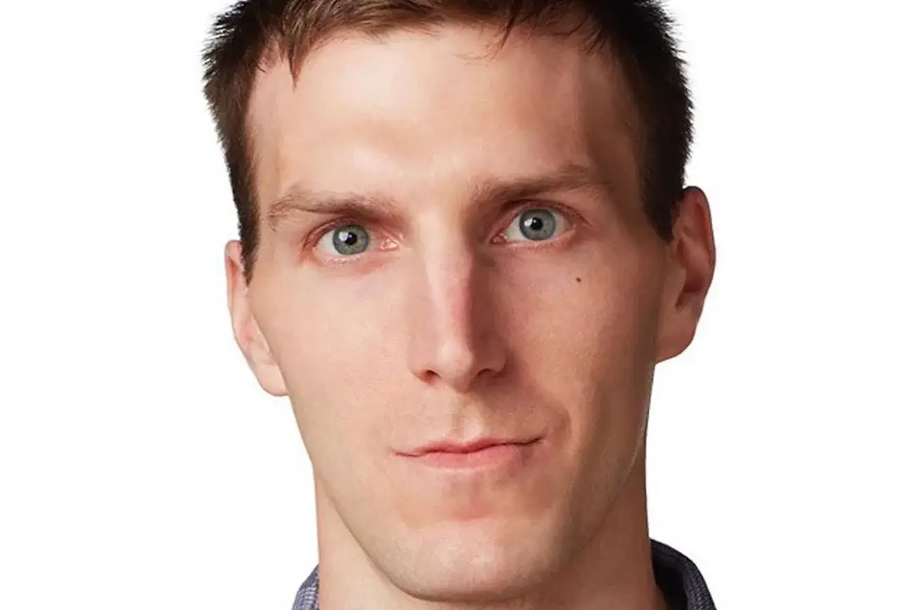 Alex Breaux with light brown hair and blue eyes, looking at the camera.
