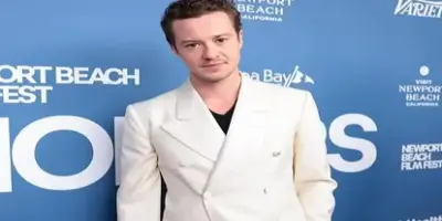 A photo of actor Joseph Quinn at a Newport Beach Film Festival event, wearing a white double-breaste