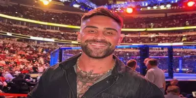 Troy Candy smiling at a camera, with an MMA ring and a crowd in the background.