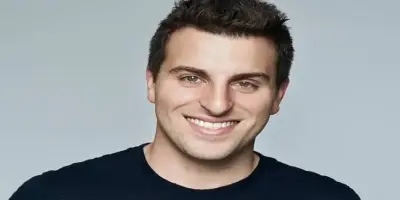 A smiling headshot portrait of Brian Chesky, co-founder and CEO of Airbnb.