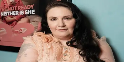 A filmmaker Lena Dunham, has long dark hair and wearing a light pink lacy blouse.