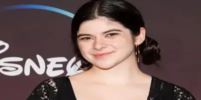 Actress Gabriella Pizzolo, who is smiling and wearing large hoop earrings and a black lacy top.