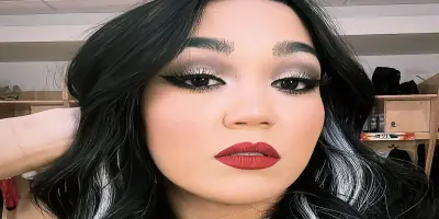 Roxanne Perez with dark hair, wearing red lipstick and a chain necklace.