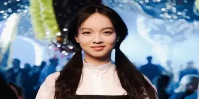 A Lucie Zhang with pigtails and a white shirt smiling at the camera.