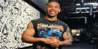 A smiling Aaron Pierre wearing a sleeveless t-shirt and glasses.