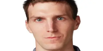 Alex Breaux with light brown hair and blue eyes, looking at the camera.