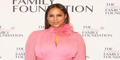 Zawe Ashton poses in a pink dress with a ruffled flower detail at the neckline.