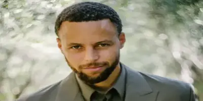 Professional basketball player Steph Curry, dressed in a muted olive suit.